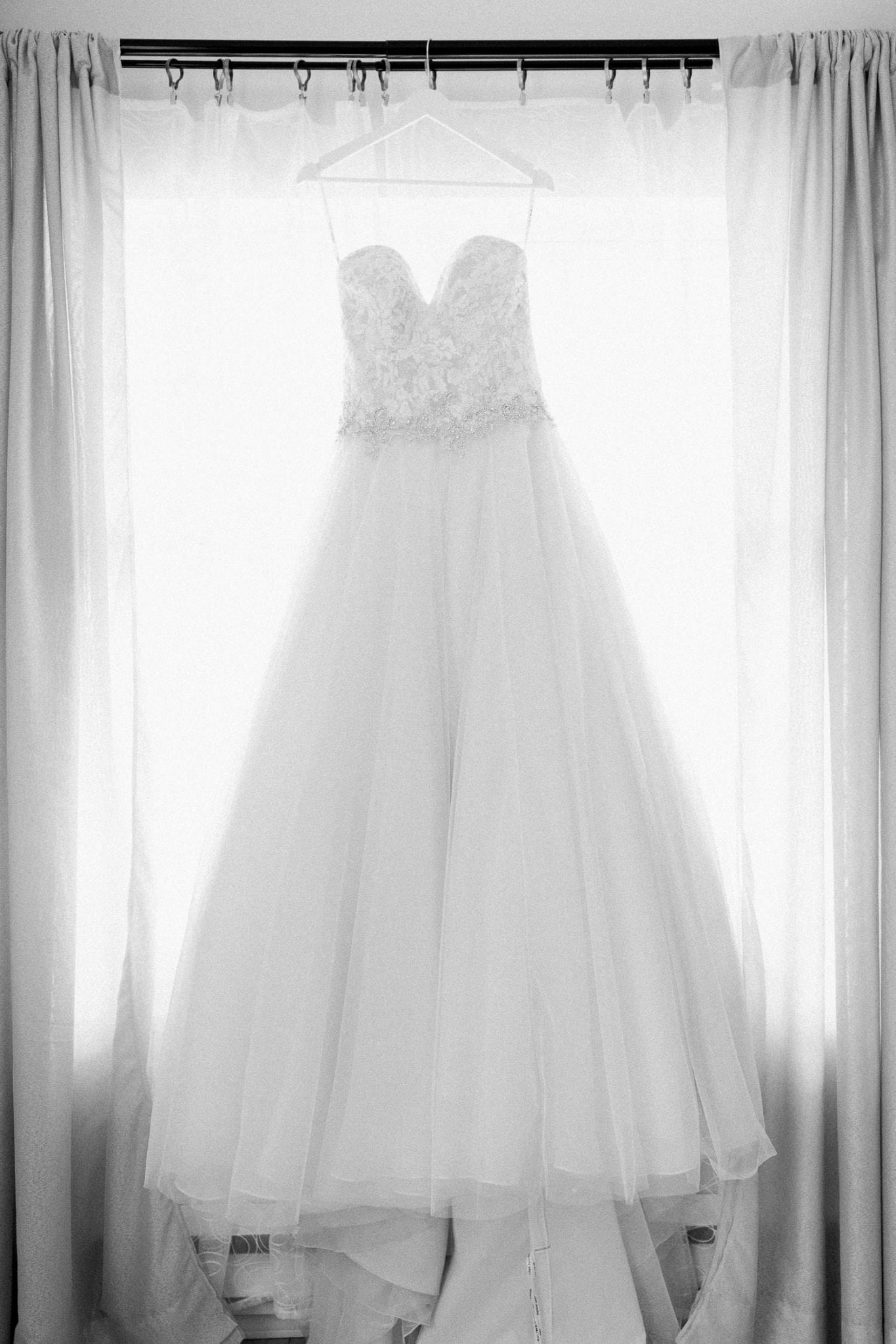 Picture of the wedding dress hanging in front of the window in b/w | Vancouver wedding photographer | Westwood Plateau Golf Club Wedding