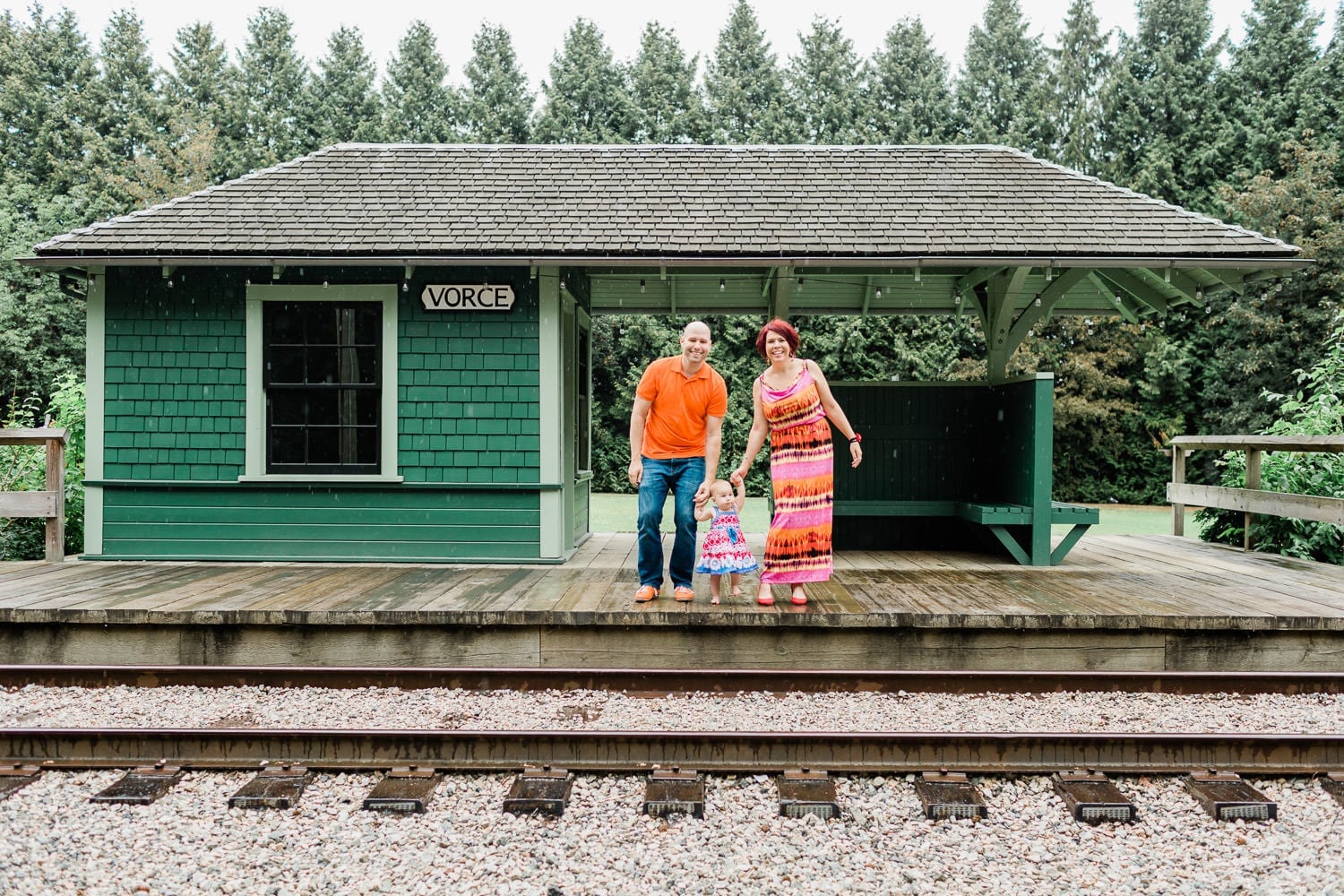 Couple standing on the old railway station holding a baby. Family Photo in Burnaby Village Museum