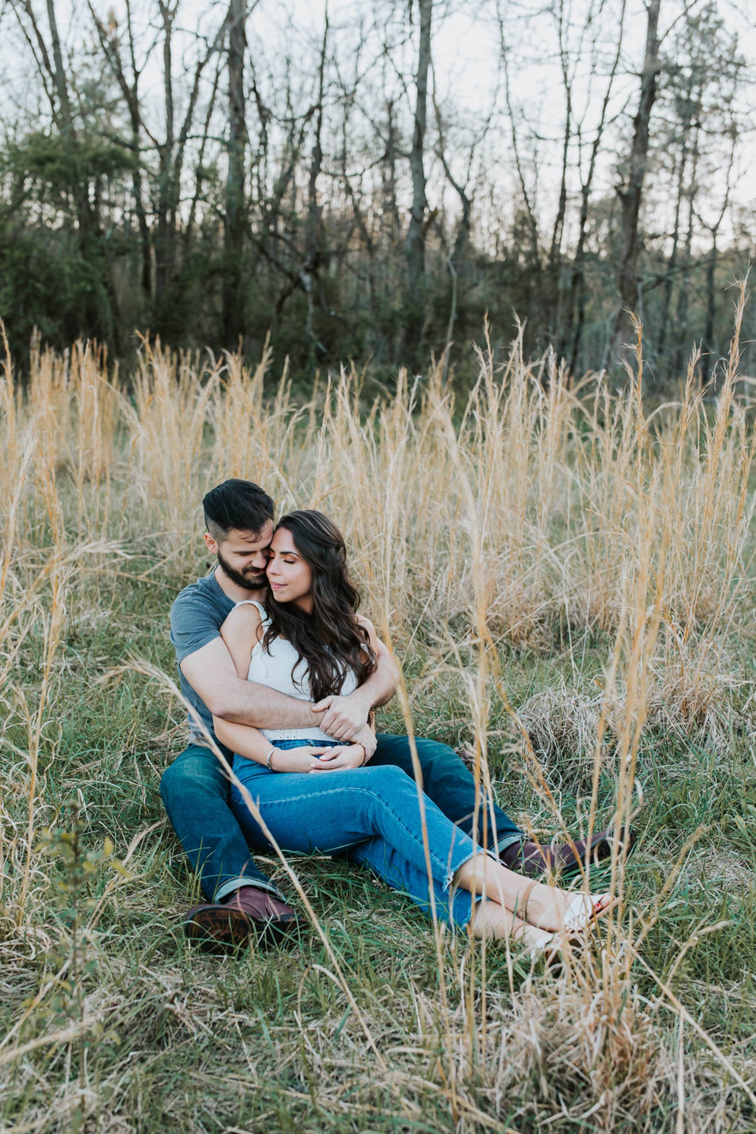 engagement couple sitting on the grass hugging